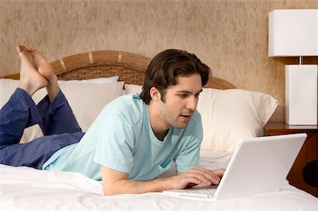 simsearch:700-00053035,k - Man Using Laptop in Bedroom Stock Photo - Rights-Managed, Code: 700-00557381