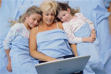 Mother and Daughters in Bed, Looking at Laptop Computer Stock Photo - Rights-Managed, Code: 700-00560910