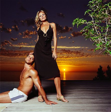 Young Man Sitting at Woman's Feet On A Patio At Sunset Foto de stock - Con derechos protegidos, Código: 700-00606416