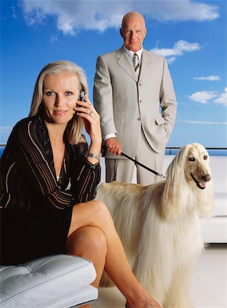 senior couple with pet - Woman Using Cell Phone, Man Standing in Background with Dog Stock Photo - Rights-Managed, Code: 700-00607383