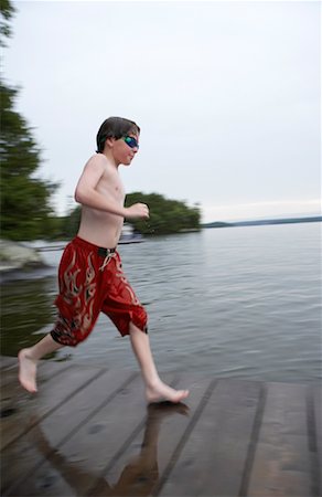 Boy Running Along Deck, Lake Rosseau, Muskoka, Ontario, Canada Foto de stock - Direito Controlado, Número: 700-00611111