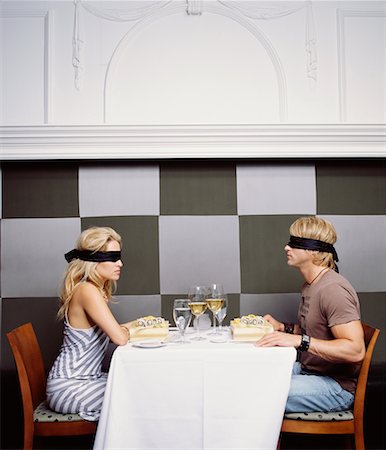 blindfolded woman sitting at a table - SuperStock