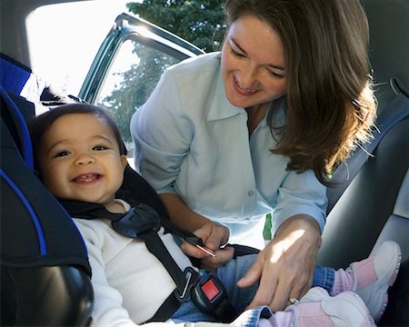 Mother Buckling Daughter into Car Seat Stock Photo - Rights-Managed, Code: 700-00634135