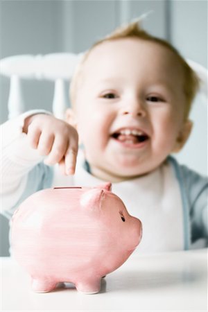 Baby in Highchair Pointing At Piggy Bank Foto de stock - Direito Controlado, Número: 700-00768882