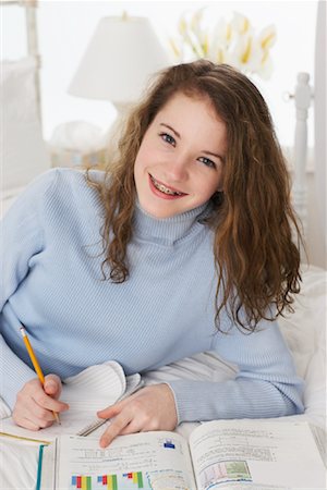 simsearch:700-00439296,k - Jeune fille à faire leurs devoirs sur le lit Photographie de stock - Rights-Managed, Code: 700-00865144