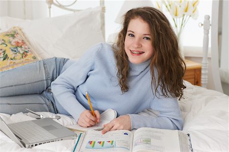 simsearch:700-00439296,k - Jeune fille à faire leurs devoirs sur le lit Photographie de stock - Rights-Managed, Code: 700-00865145