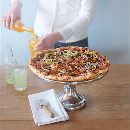 Woman Pouring Juice with Pizza on the Table Stock Photo - Rights-Managed, Code: 700-00866526