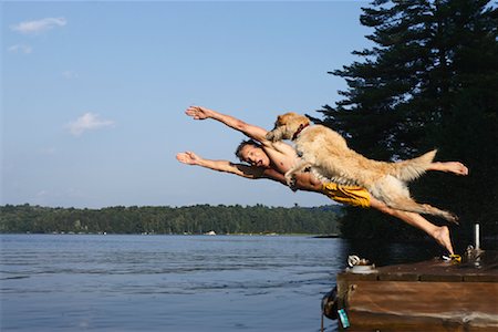 Man Jumping off Deck With Dog Fotografie stock - Rights-Managed, Codice: 700-00867017