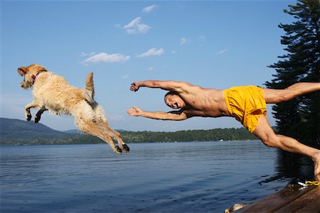 Man Jumping off Deck With Dog Fotografie stock - Rights-Managed, Codice: 700-00867018