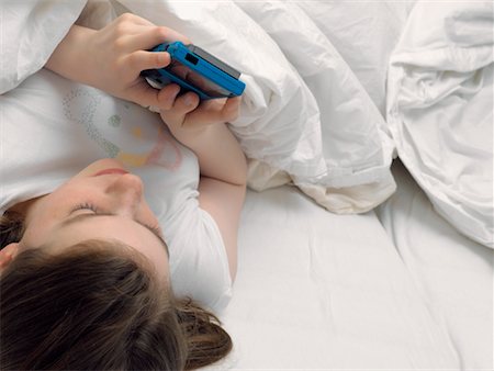 simsearch:700-01182792,k - Girl Lying in Bed, Playing Video Games Stock Photo - Rights-Managed, Code: 700-00918305