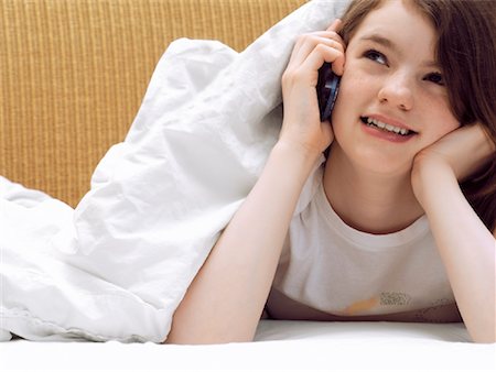 Girl Lying in Bed, Talking on Cell Phone Stock Photo - Rights-Managed, Code: 700-00918310