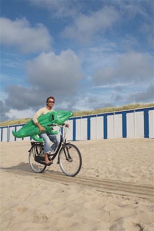 Man Riding Bicycle and Carrying Inflatable Crocodile on Beach Foto de stock - Con derechos protegidos, Código: 700-01042791