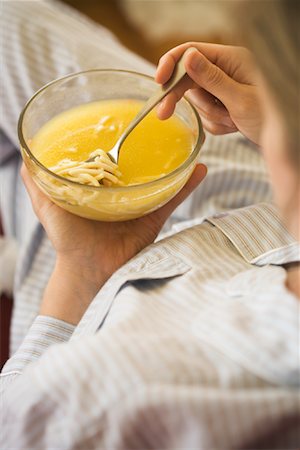 Sick Woman Eating Chicken Noodle Soup in Pyjamas Stock Photo - Rights-Managed, Code: 700-01043686