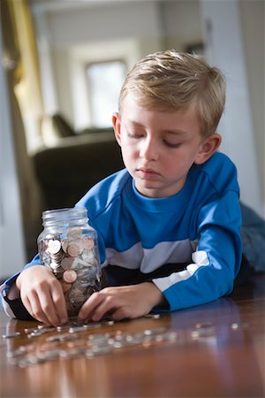 Boy Lying on Floor Counting Coins Foto de stock - Con derechos protegidos, Código: 700-01120593