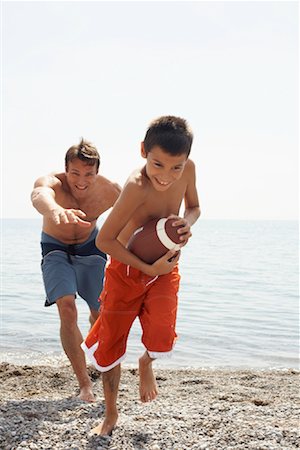 picture of father and son playing foot ball - Father and Son Playing Football At Beach Foto de stock - Con derechos protegidos, Código: 700-01183162
