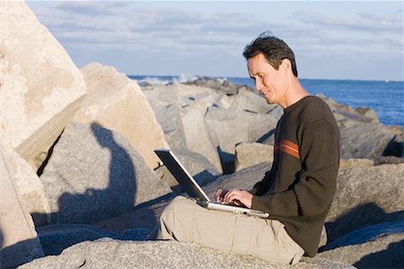 Homme utilisant un ordinateur portable à la plage Photographie de stock - Rights-Managed, Code: 700-01615324