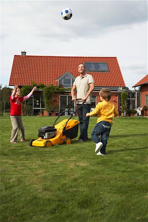 family house three people outdoors play - Dad Mowing the Lawn While Kids Play Soccer Stock Photo - Rights-Managed, Code: 700-01716504