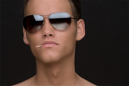 simsearch:700-02080491,k - Close-up Portrait d'un homme portant des lunettes de soleil avec une allumette dans la bouche Photographie de stock - Rights-Managed, Code: 700-02082072