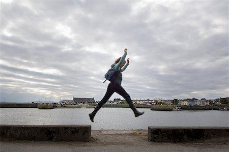 sauter de joie - Femme sautant sur le trottoir de l'eau, baie de Galway, Galway, comté de Galway, Irlande Photographie de stock - Rights-Managed, Code: 700-02289023