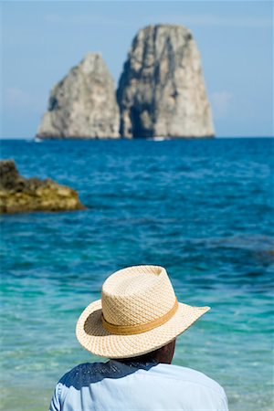 Mann sitzt am Strand, die Faraglioni in der Distanz, Golf von Neapel, Capri, Neapel, Campania, Italien Stockbilder - Lizenzpflichtiges, Bildnummer: 700-02289527