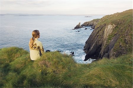 Woman Sitting on Cliff by the Celtic Sea, Cape Clear Island, County Cork, Ireland Foto de stock - Con derechos protegidos, Código: 700-02348642