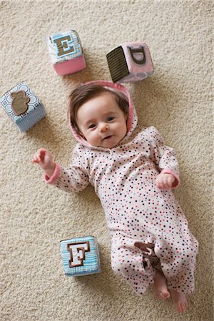 Baby Girl Lying on Floor, Surrounded by Toy Blocks Stock Photo - Rights-Managed, Code: 700-02386069
