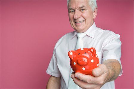 senior and saving - Man Holding Out Piggy Bank Foto de stock - Con derechos protegidos, Código: 700-02637510