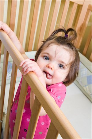 Portrait de bébé fille debout dans le lit d'enfant Photographie de stock - Rights-Managed, Code: 700-02633421