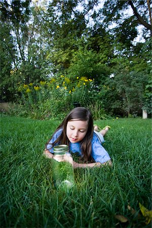 Girl Lying on Grass Looking at Jar of Fireflies Stock Photo - Rights-Managed, Code: 700-02698409