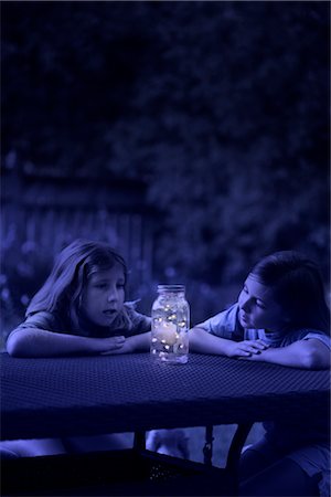 Filles regardant bocal de lucioles dans la nuit Photographie de stock - Rights-Managed, Code: 700-02698415