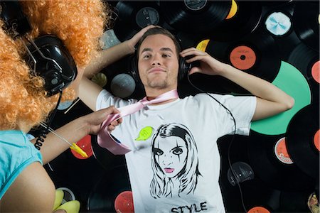 retro person listening music - Man Lying on Pile of Records, Woman Pulling Him Up By His Necktie Stock Photo - Rights-Managed, Code: 700-02693770