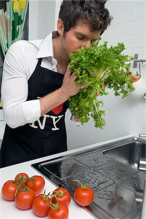 Man in Kitchen Washing Vegetables and Smelling Fresh Lettuce Foto de stock - Con derechos protegidos, Código: 700-02756600