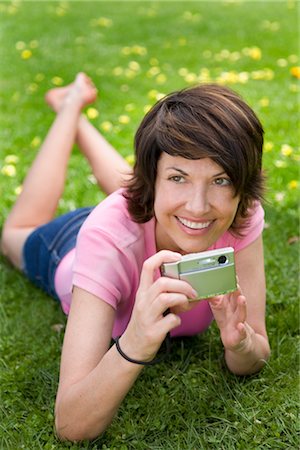 Woman Lying on the Ground Holding Digital Camera Stock Photo - Rights-Managed, Code: 700-02833587
