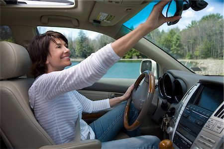 dirección (conducir) - Driver Adjusting Rear-view Mirror Foto de stock - Con derechos protegidos, Código: 700-02833581