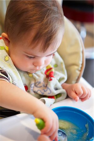 Boy with Down Syndrom Sitting in High Chair, Eating Stock Photo - Rights-Managed, Code: 700-02833653