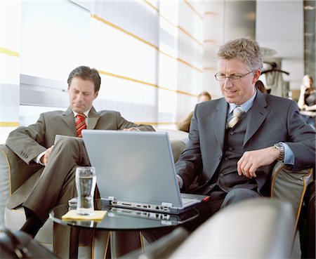 smiling brunette man looking at laptop - Business People Waiting in Airport Lounge Stock Photo - Rights-Managed, Code: 700-02887151