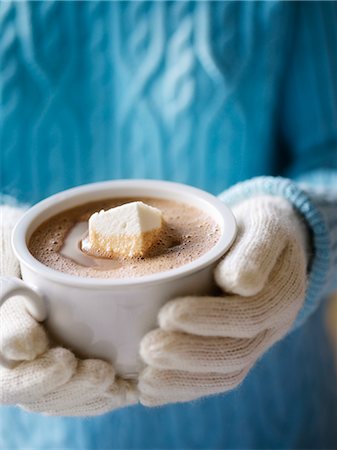 Frau trägt einen Pullover und Fäustlinge halten einer Tasse heißer Schokolade mit einem hausgemachten Marshmallow Stockbilder - Lizenzpflichtiges, Bildnummer: 700-02883260