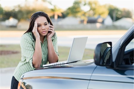 Frustrated Businesswoman Leaning on Hood of Car, Using Laptop Computer and Talking on Cell Phone Foto de stock - Con derechos protegidos, Código: 700-02912040
