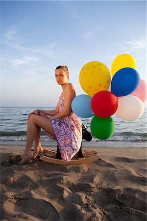 Woman With Colourful Balloons Sitting on a Rocking Horse on the Beach Foto de stock - Con derechos protegidos, Código: 700-02943253