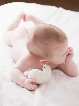 entrañable - Baby Lying on Bed With Toy Foto de stock - Con derechos protegidos, Código: 700-02943473