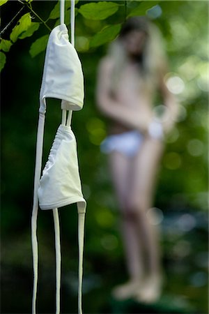 people with forest background - Bikini Top Hanging From Tree Branch, Woman in the Background Stock Photo - Rights-Managed, Code: 700-02990192