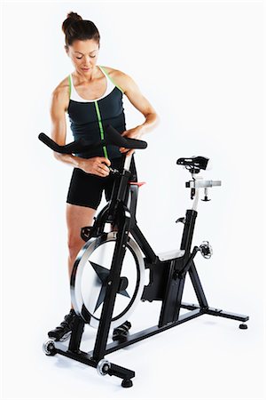 sweaty women in spandex - Woman Adjusting Stationary Bicycle Stock Photo - Rights-Managed, Code: 700-03004414