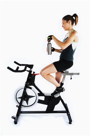 sweaty women - Woman Riding Stationary Bicycle and Drinking Water Foto de stock - Con derechos protegidos, Código: 700-03004421