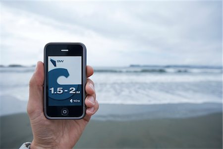 smart phones canadian photos - Man Holding Smartphone Showing Surf Report Stock Photo - Rights-Managed, Code: 700-03152436