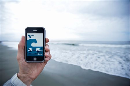 smart phones canadian photos - Man Holding Smartphone Showing Surf Report Stock Photo - Rights-Managed, Code: 700-03152437