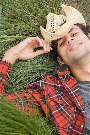 Porträt von Mann mit Cowboyhut und liegend auf Gras Stockbilder - Lizenzpflichtiges, Bildnummer: 700-03290297