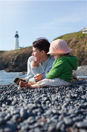 sonnenhut - Mutter und Baby Tochter sitzt am Strand, mit Yaquina Head Lighthouse in der Ferne, in der Nähe von Newport, Oregon, USA Stockbilder - Lizenzpflichtiges, Bildnummer: 700-03439523
