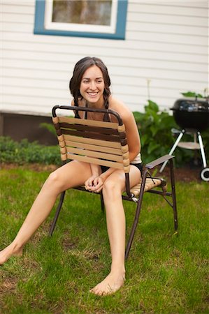 Woman Sitting Backwards on Lawn Chair in Backyard Foto de stock - Con derechos protegidos, Código: 700-03613011