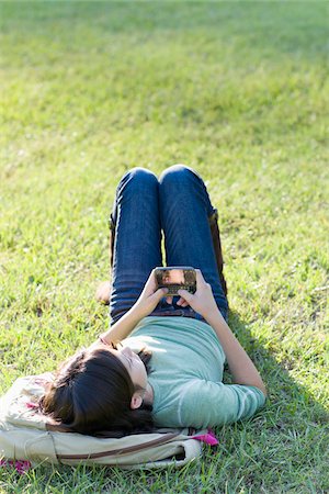 Fille avec téléphone cellulaire couché sur l'herbe Photographie de stock - Rights-Managed, Code: 700-03719311