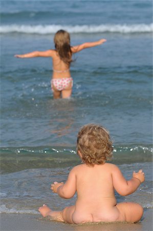 simsearch:700-03696878,k - Naked Baby Sitting on Beach and Girl with Outstretched Arms Wading in Water Stock Photo - Rights-Managed, Code: 700-03739260